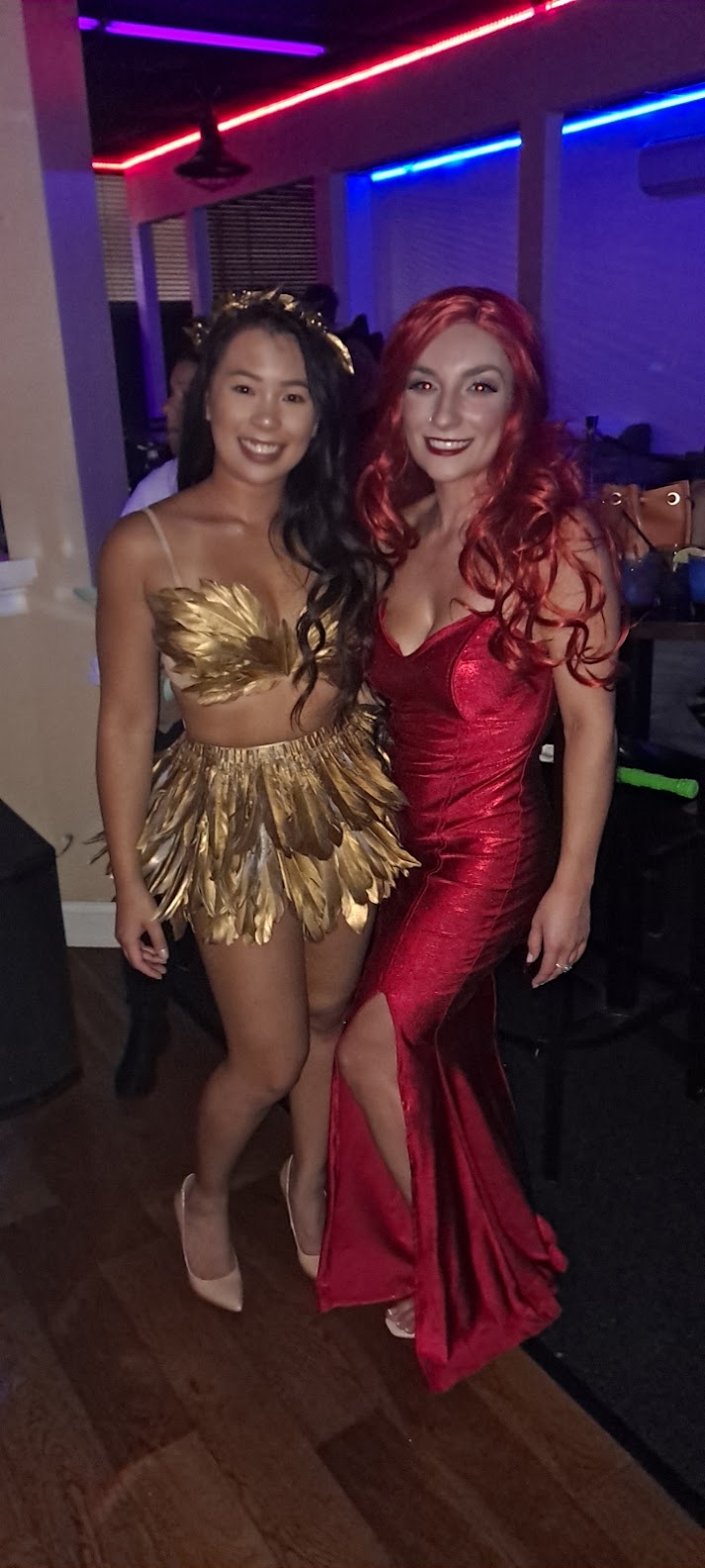 Two women in red and gold costumes posing for a photo.