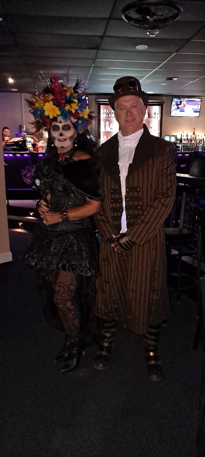 A man and woman dressed as skeletons in a bar.