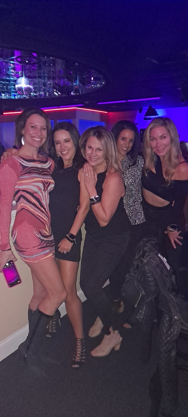 A group of women posing for a picture in a club.